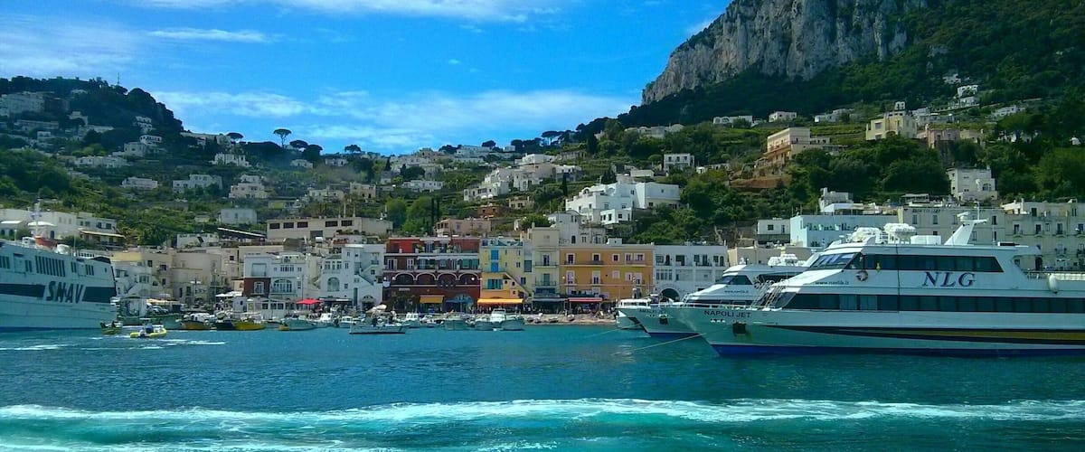A coastal town with colorful buildings, boats, and a mountainous backdrop.
