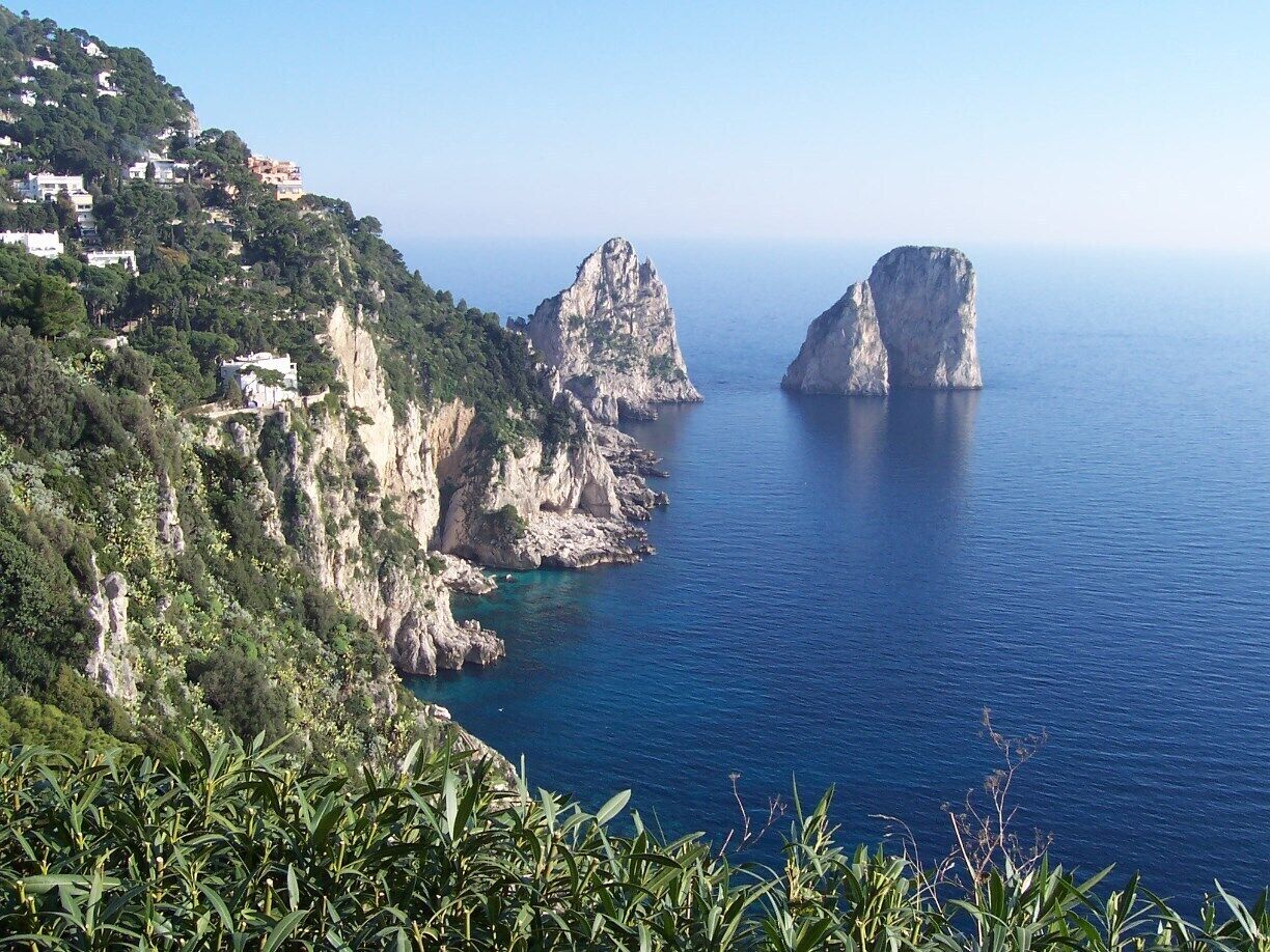 A coastal landscape with rocky cliffs and a clear blue sea.
