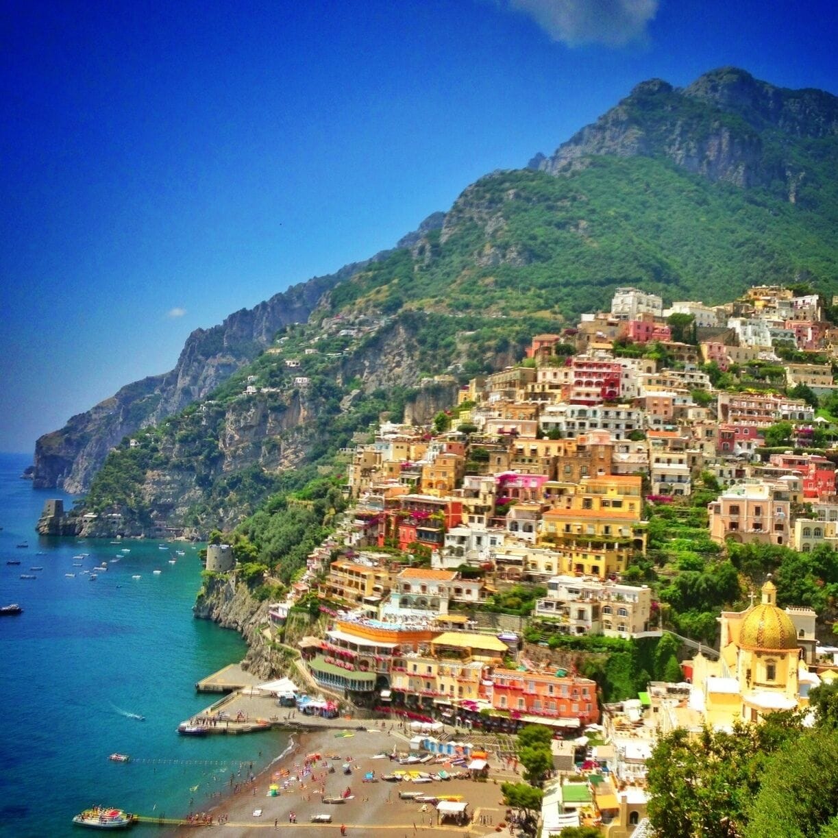 A coastal town with colorful buildings, a beach, and boats in the water.
