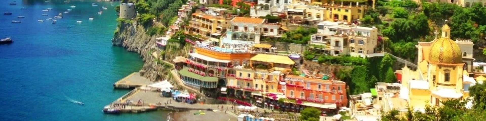 A coastal town with colorful buildings, a beach, and boats in the water.