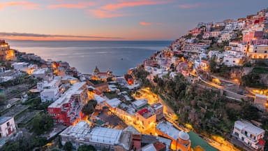 A coastal town at dusk with buildings along the hillside and a view of the sea.