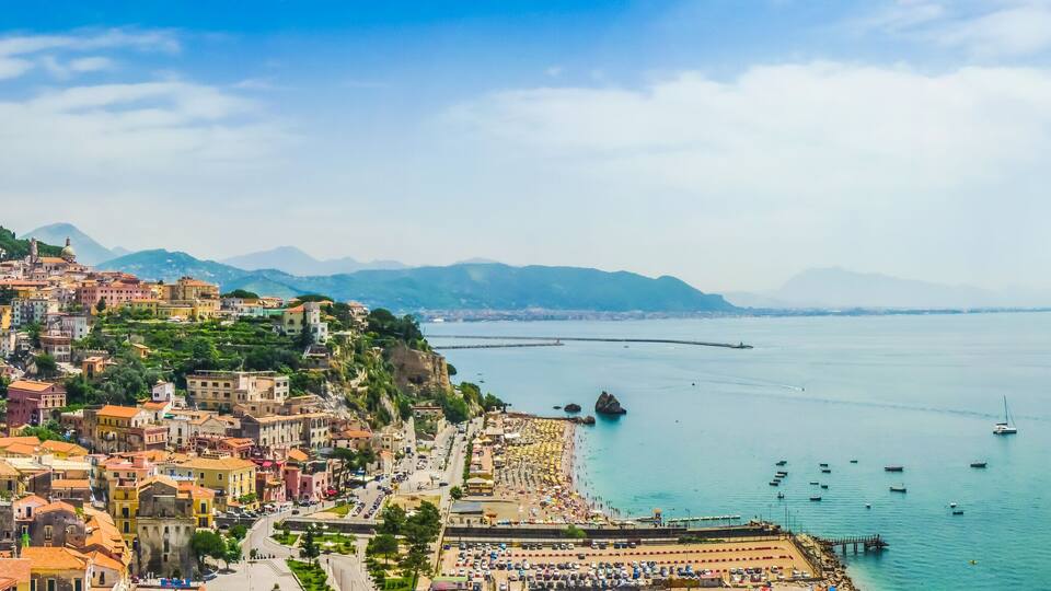 A coastal town with colorful buildings, a beach, and a calm sea.