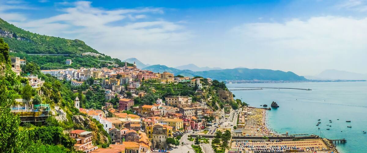 A coastal town with colorful buildings, a beach, and a calm sea.