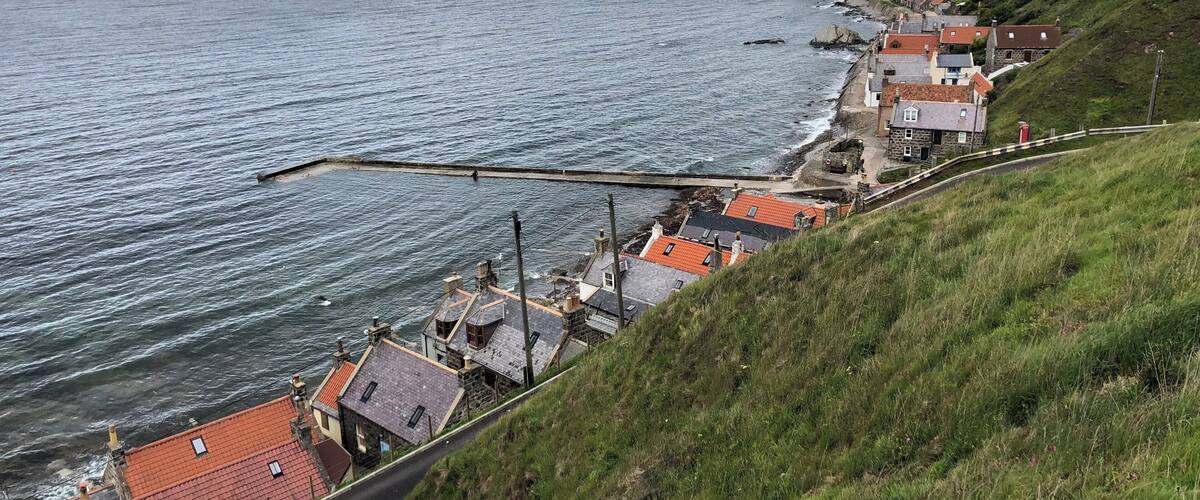 A coastal village with houses along the hillside and a pier extending into the sea.