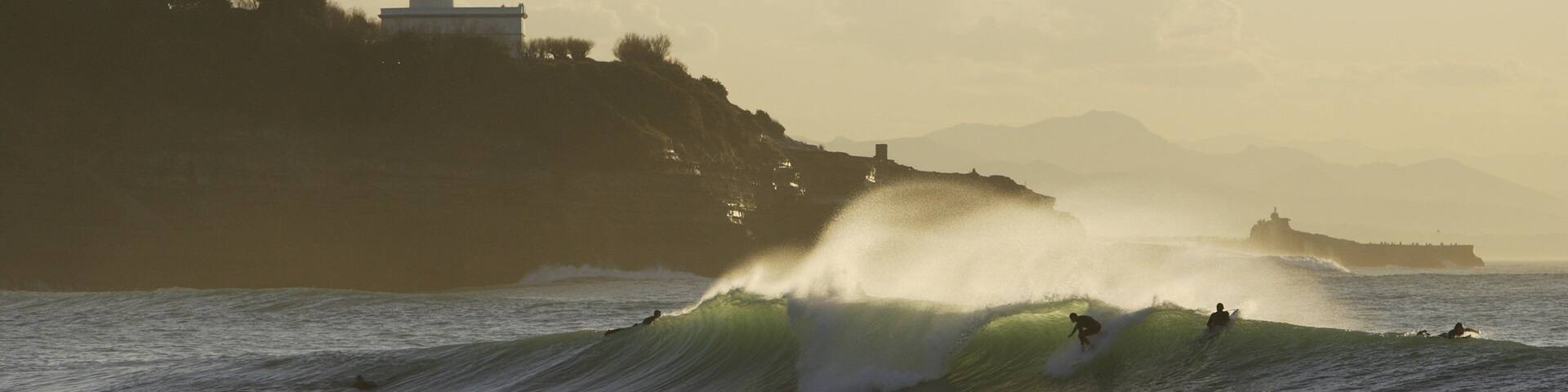 Anglet som viser klippekystlinje, bølger og et fyrtårn