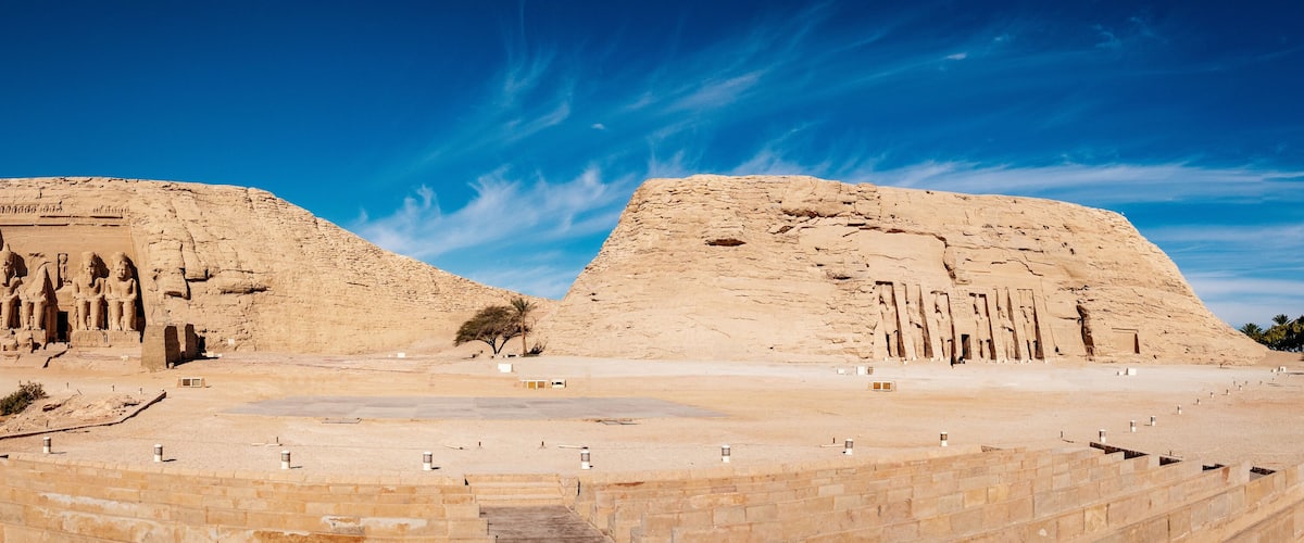 A large, ancient pyramid with hieroglyphs and statues, surrounded by a desert landscape.
