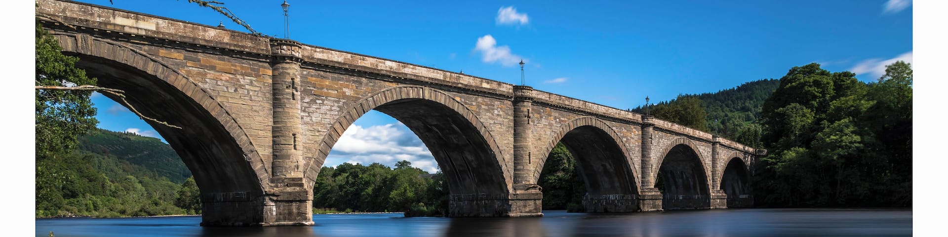 a photo of the historic bridge at Dunkeld with the river meandering along through the town