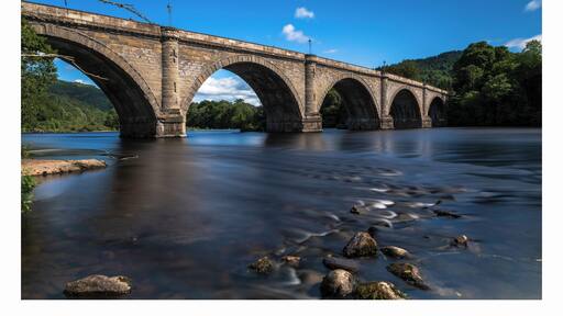 a photo of the historic bridge at Dunkeld with the river meandering along through the town