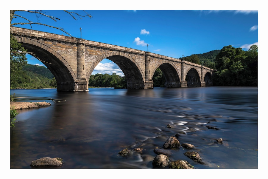 a photo of the historic bridge at Dunkeld with the river meandering along through the town