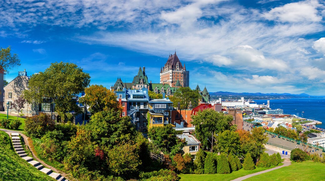 A coastal cityscape with historic architecture, a waterfront promenade, and a large body of water.