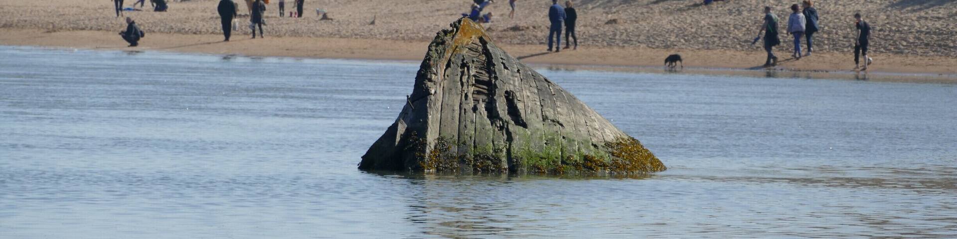 the remains of a sunken boat lie submerged in the river Ythan near Newburgh .