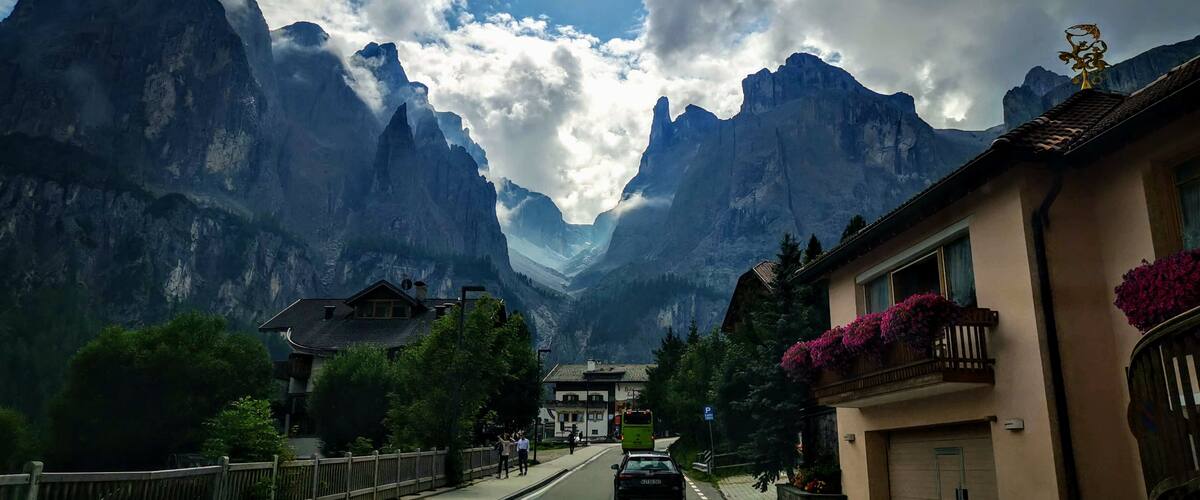 A mountain road with a car, houses, and a bus.