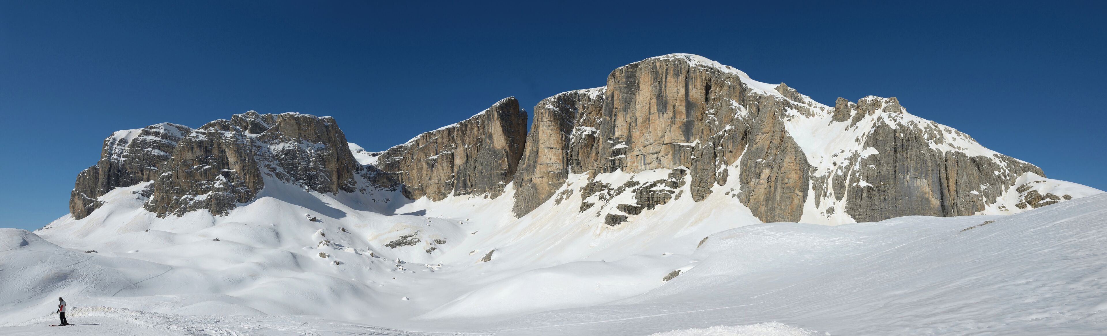 A snow-covered mountain with sharp peaks and a clear blue sky.
