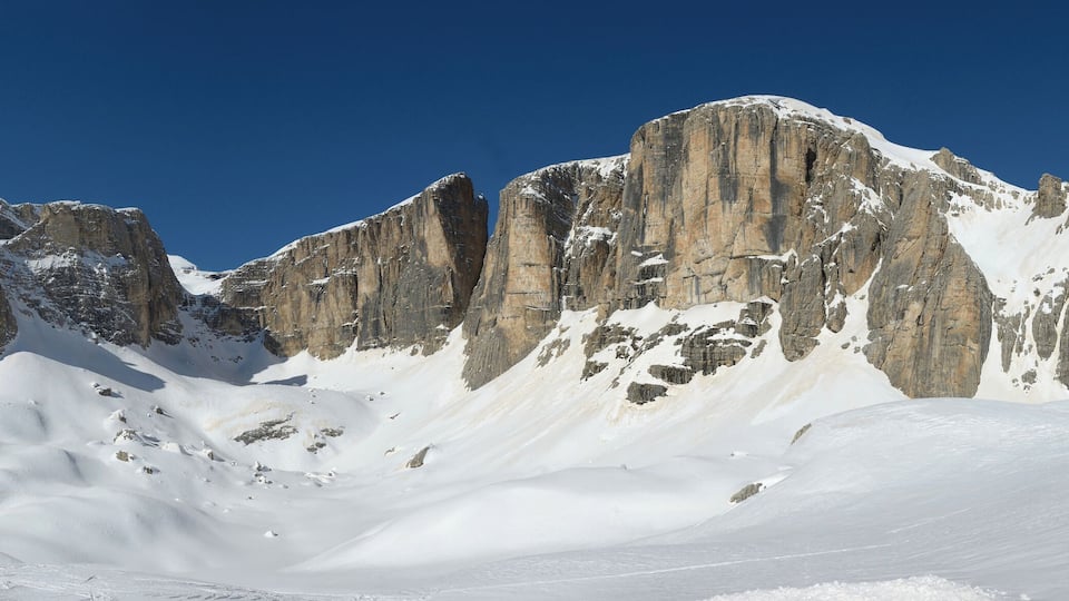 A snow-covered mountain with sharp peaks and a clear blue sky.