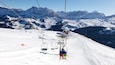 A ski lift on a snowy mountain with a clear sky.