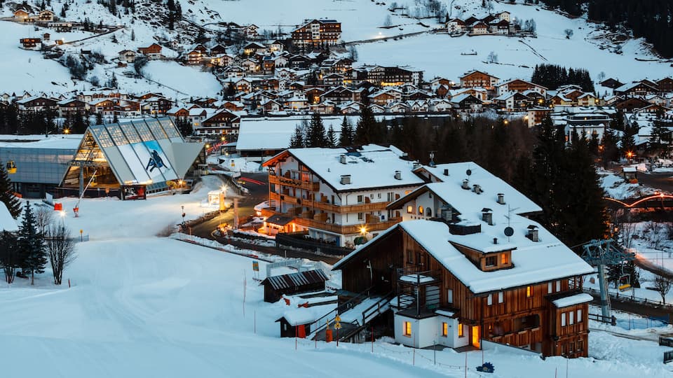 A snow-covered village with wooden houses and a ski lift.