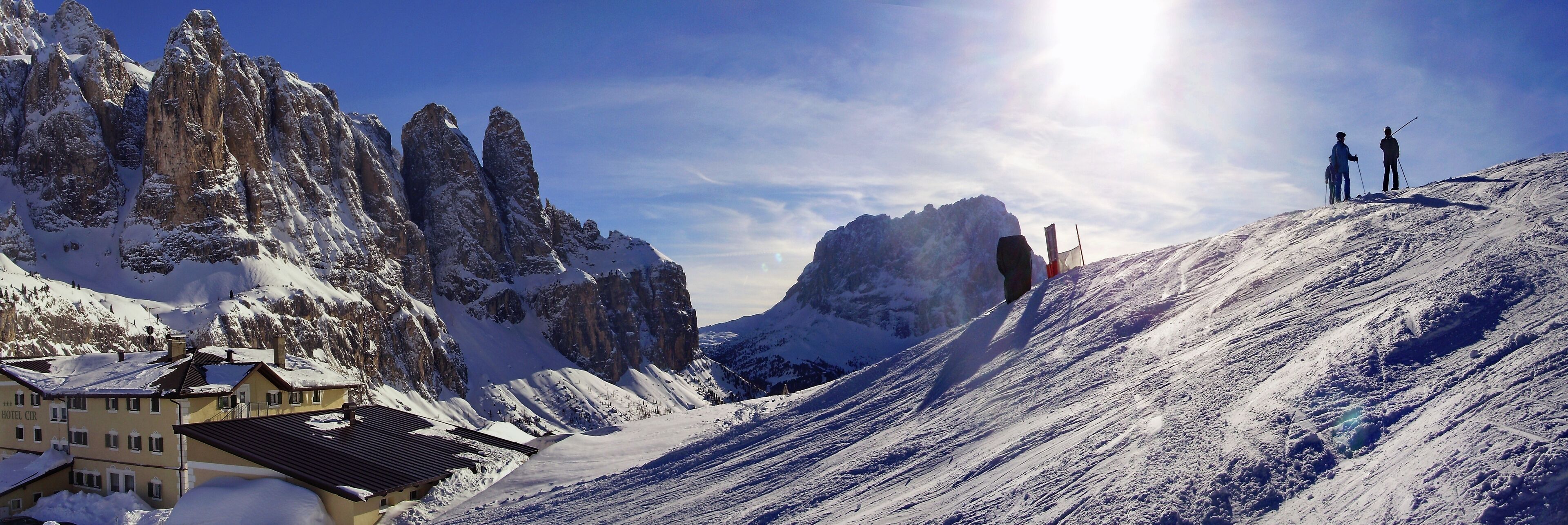 A snow-covered mountain with a hotel named "HOTEL CIR" and two skiers on a slope.