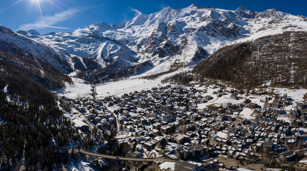 Aerial panorama of the famous Saas Fee village and ski resort by the Dom mountain, the tallest entirely in Switzerland in the alps on a sunny winter day