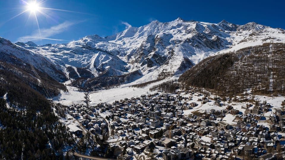A snow-covered mountain town with a clear sky and a bright sun.