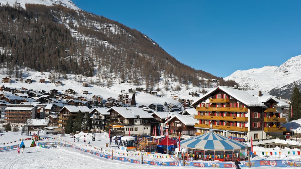 A snow-covered mountain village with wooden buildings and a ski resort.