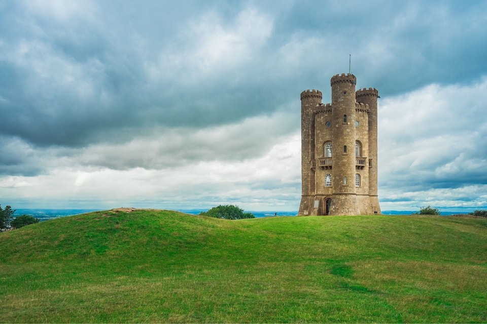 Una torre medieval sobre una colina cubierta de hierba con cielo nublado.