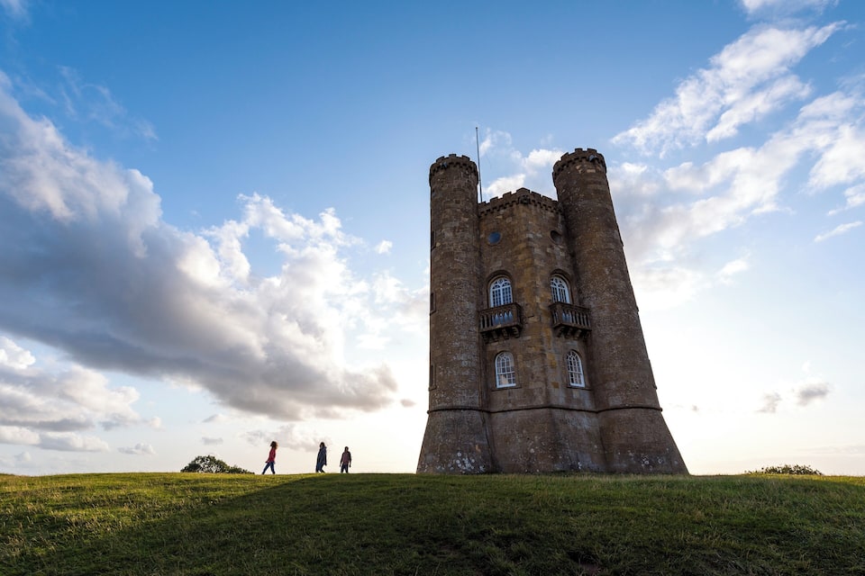 Una torre de piedra histórica con almenas, sobre un cielo despejado con algunas nubes.