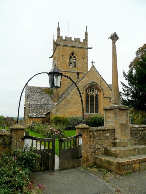 A historic church with a tall bell tower, a large stained glass window, and a stone gate.