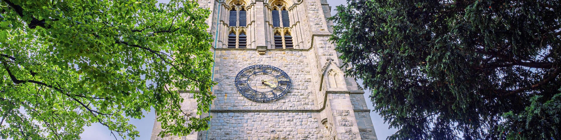 London, England, UK - August 28, 2023: View of the pinnacled tower clock of St. George's Parish medieval Church against the sky in Beckenham village