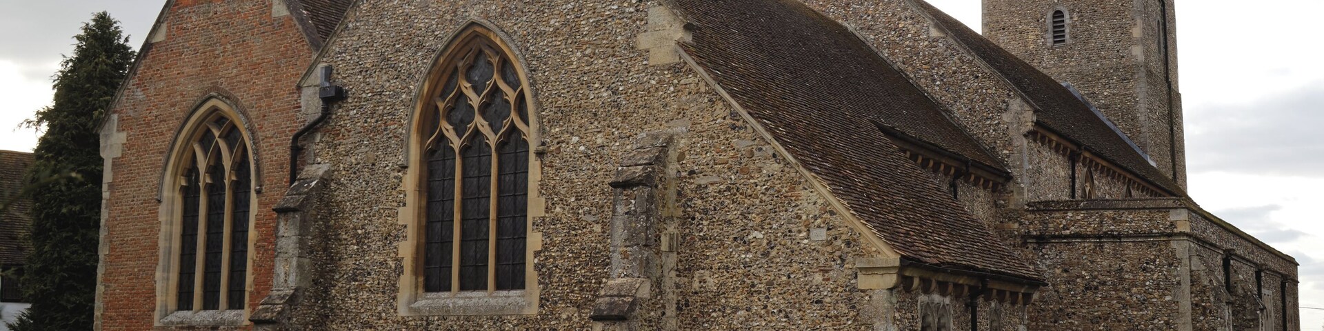 Una iglesia histórica con fachada de piedra, amplias ventanas de arco y un campanario.