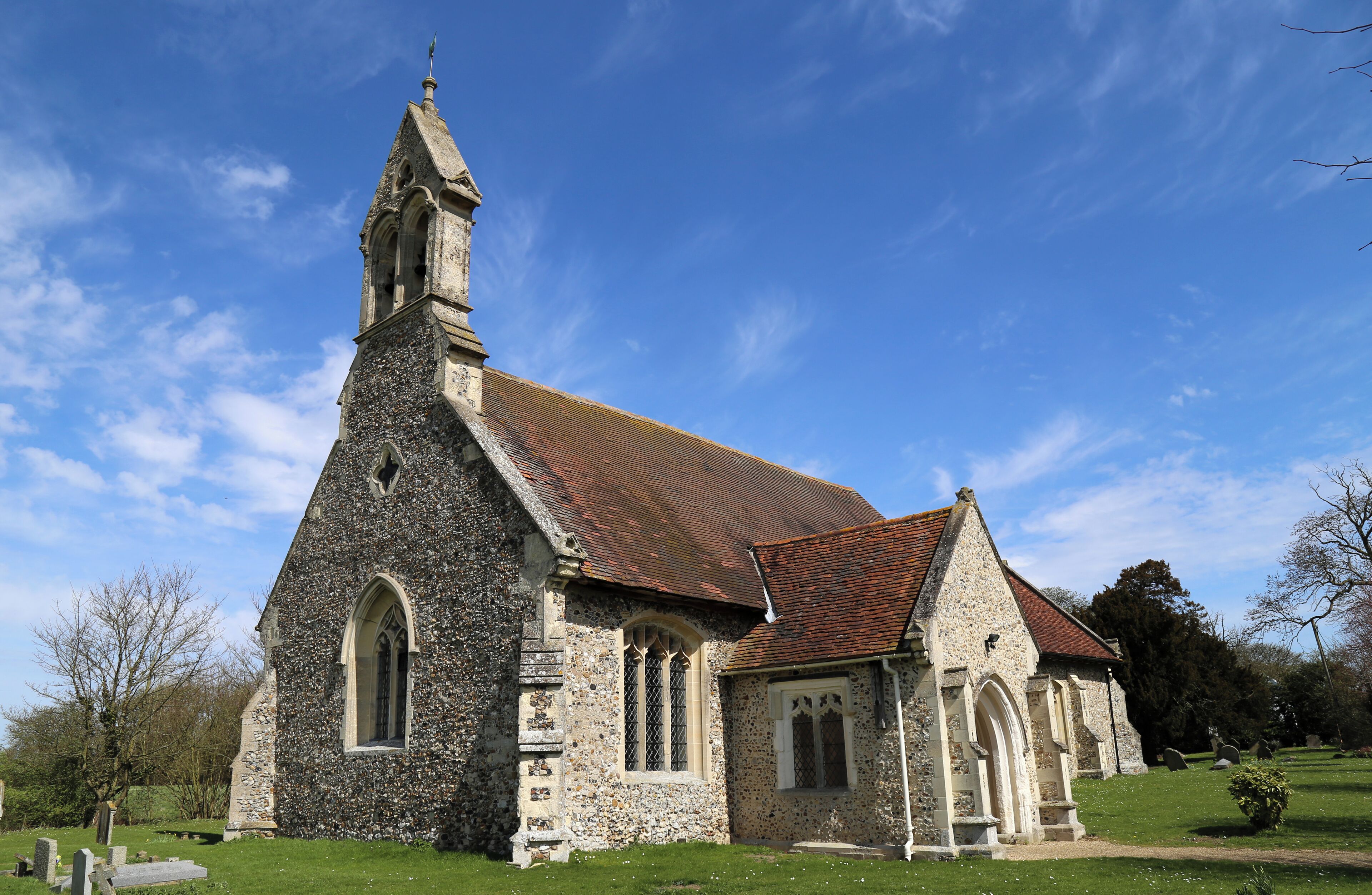 A stone church with a red-tiled roof and a tall steeple.