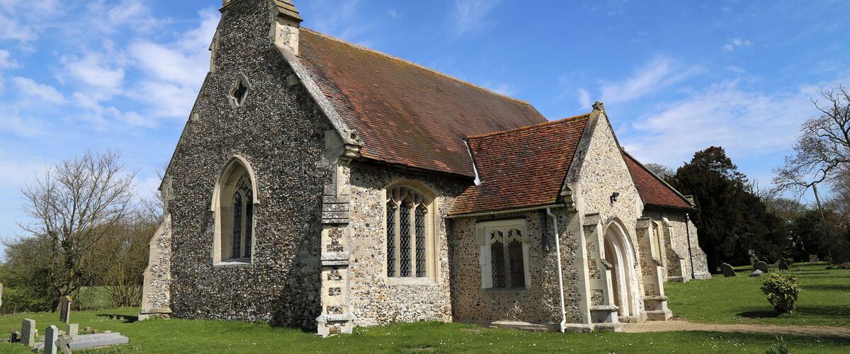 A stone church with a red-tiled roof and a tall steeple.
