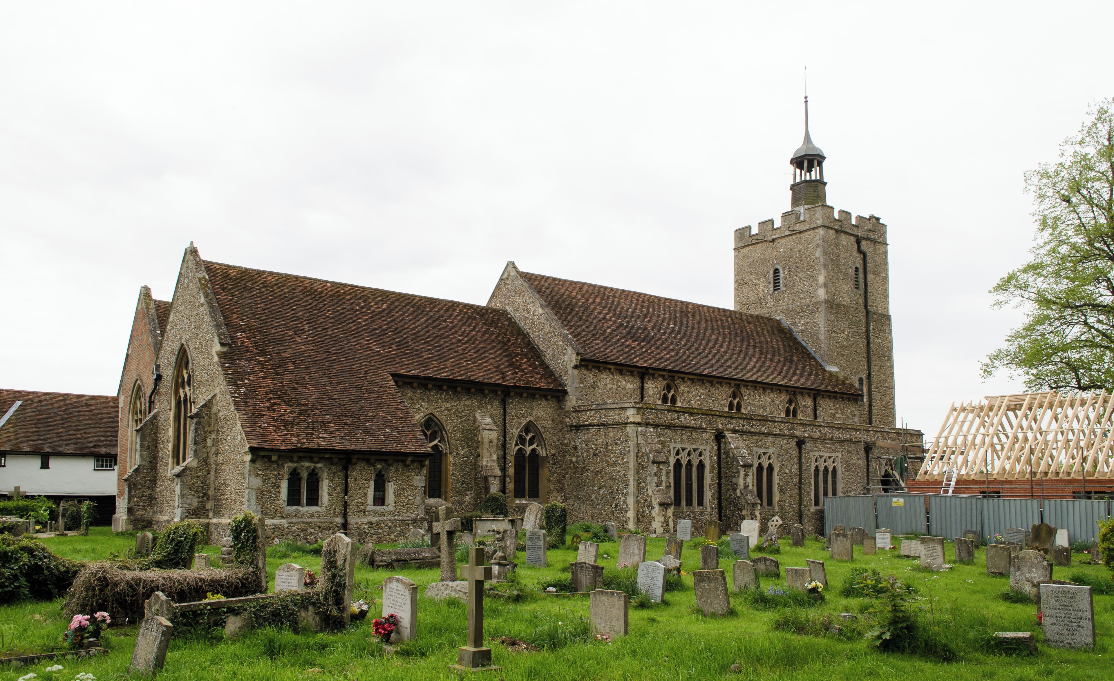 A historic church with a tall tower and a cemetery in front.