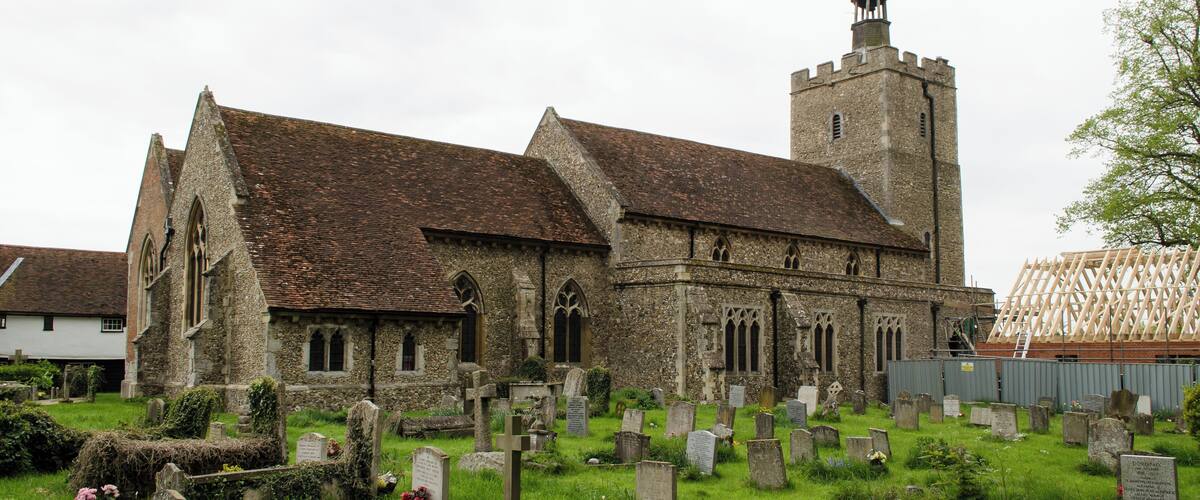 A historic church with a tall tower and a cemetery in front.