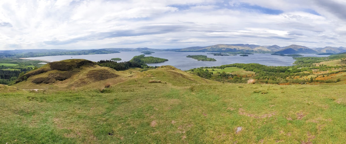 A lake surrounded by hills and a cloudy sky.