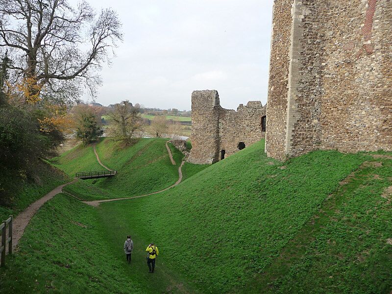 A castle on a grassy hill with a path leading to it.