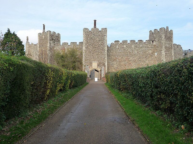 A paved pathway leading to a historic stone castle with multiple towers and a central entrance.