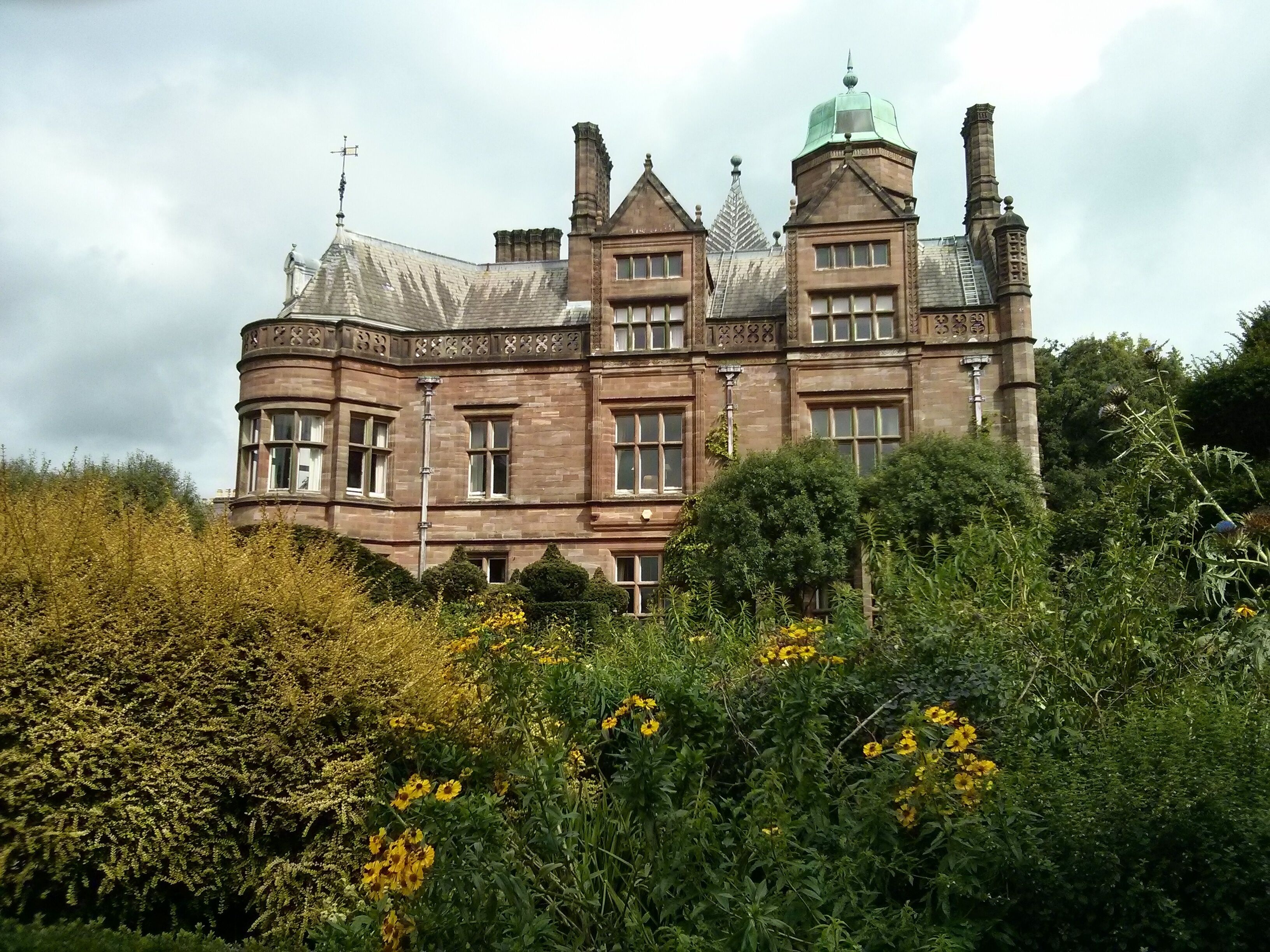 A large, historic building with multiple chimneys and a turret.