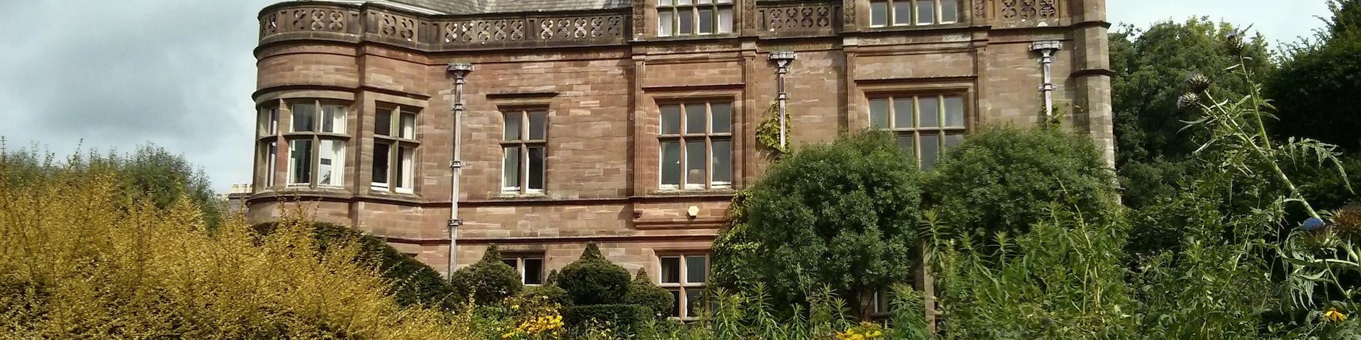 A large, historic building with multiple chimneys and a turret.
