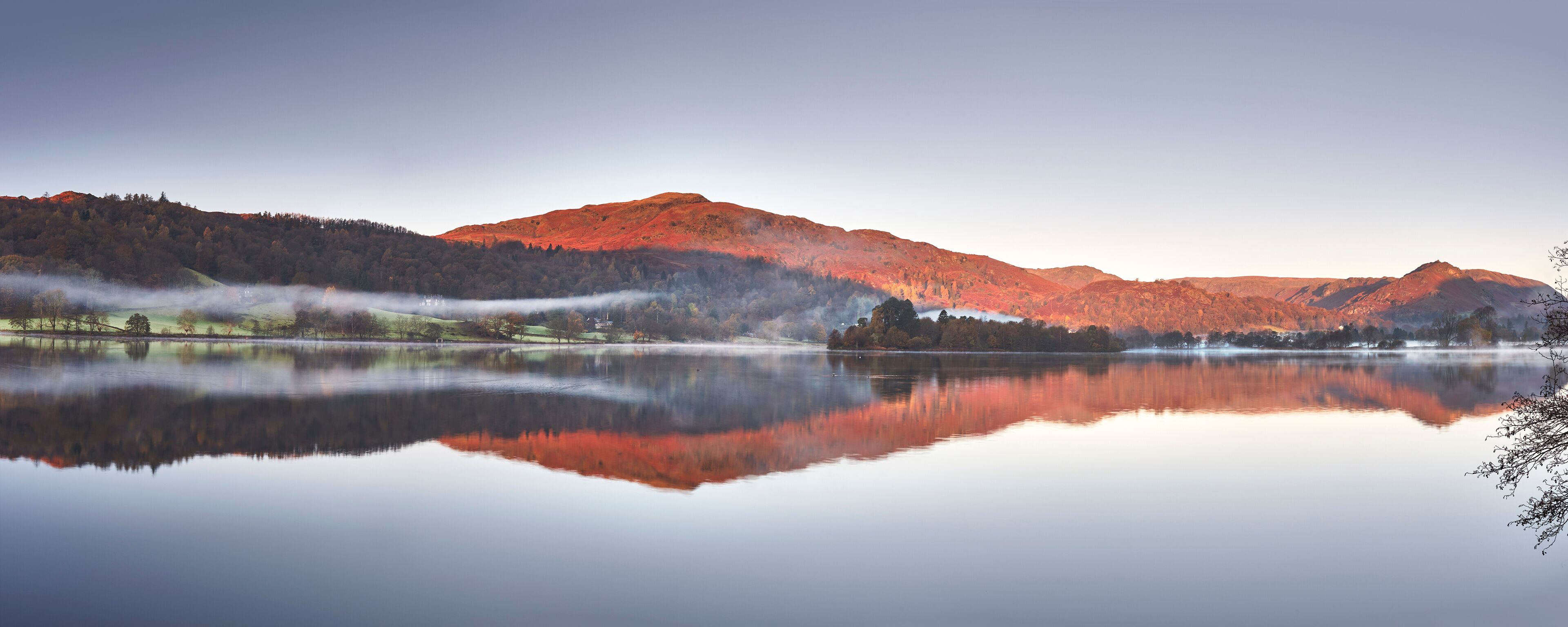 A calm lake reflecting mountains and trees.