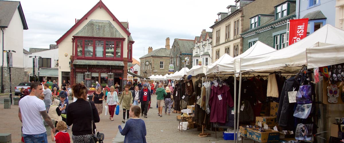A busy street market with people shopping and a variety of stalls selling clothes and other items.