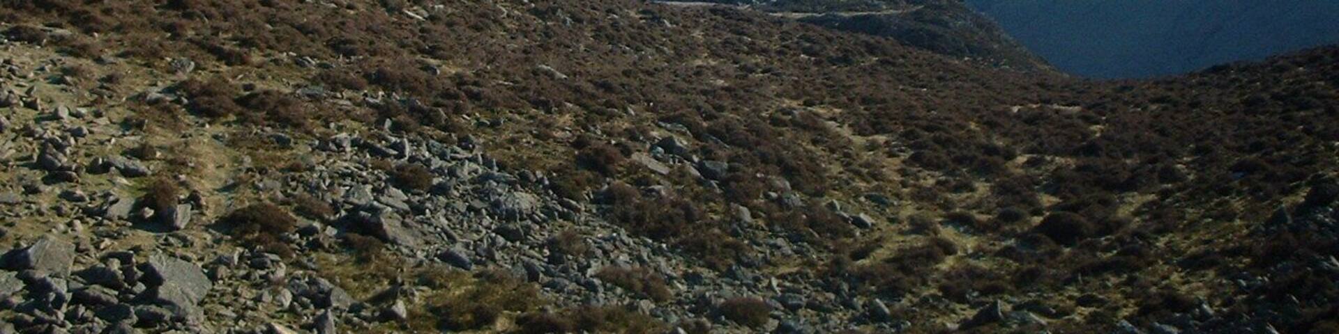 A rugged mountainous landscape with rocky terrain and sparse vegetation.