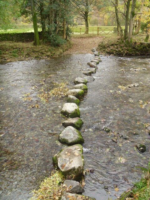 Un puente de piedra sobre un arroyo con un paisaje rural de fondo.