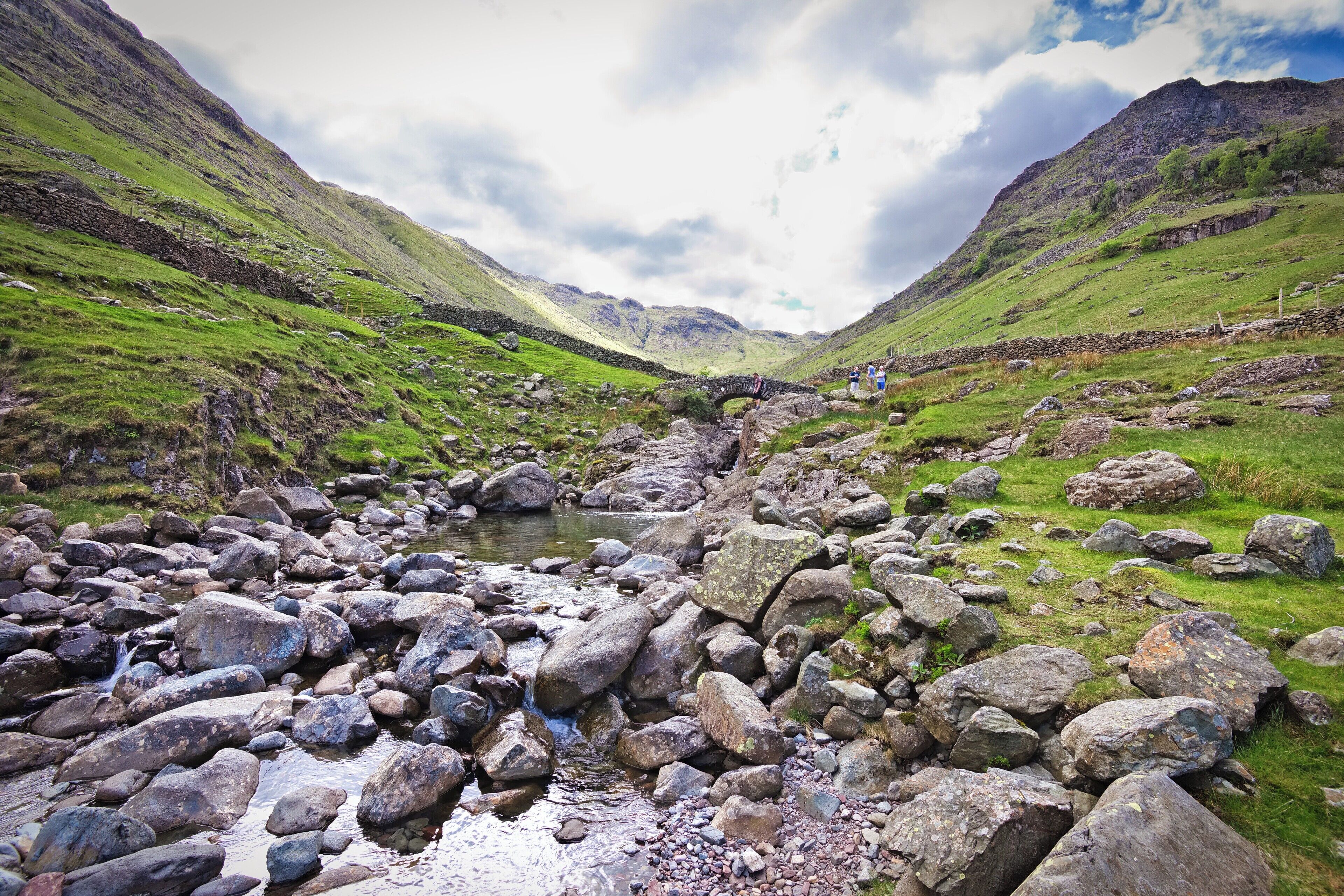 A rocky stream in a valley with mountains in the background.