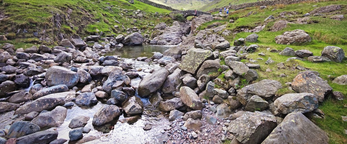 A rocky stream in a valley with mountains in the background.