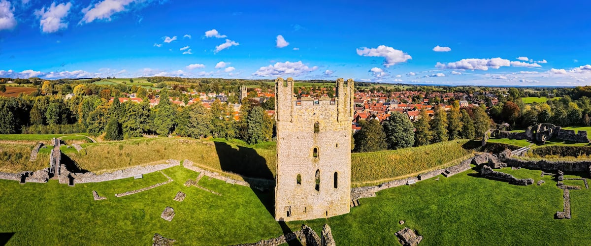 A medieval castle surrounded by a lush green landscape and a small village in the background.