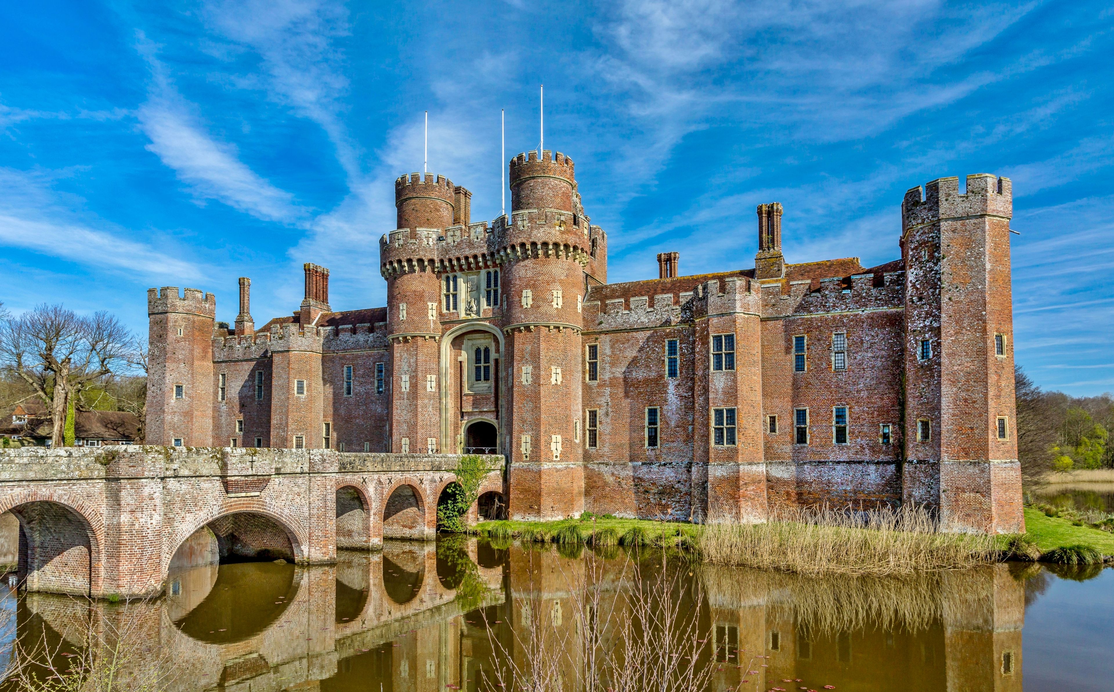 A historic castle with multiple towers, a bridge, and a moat.