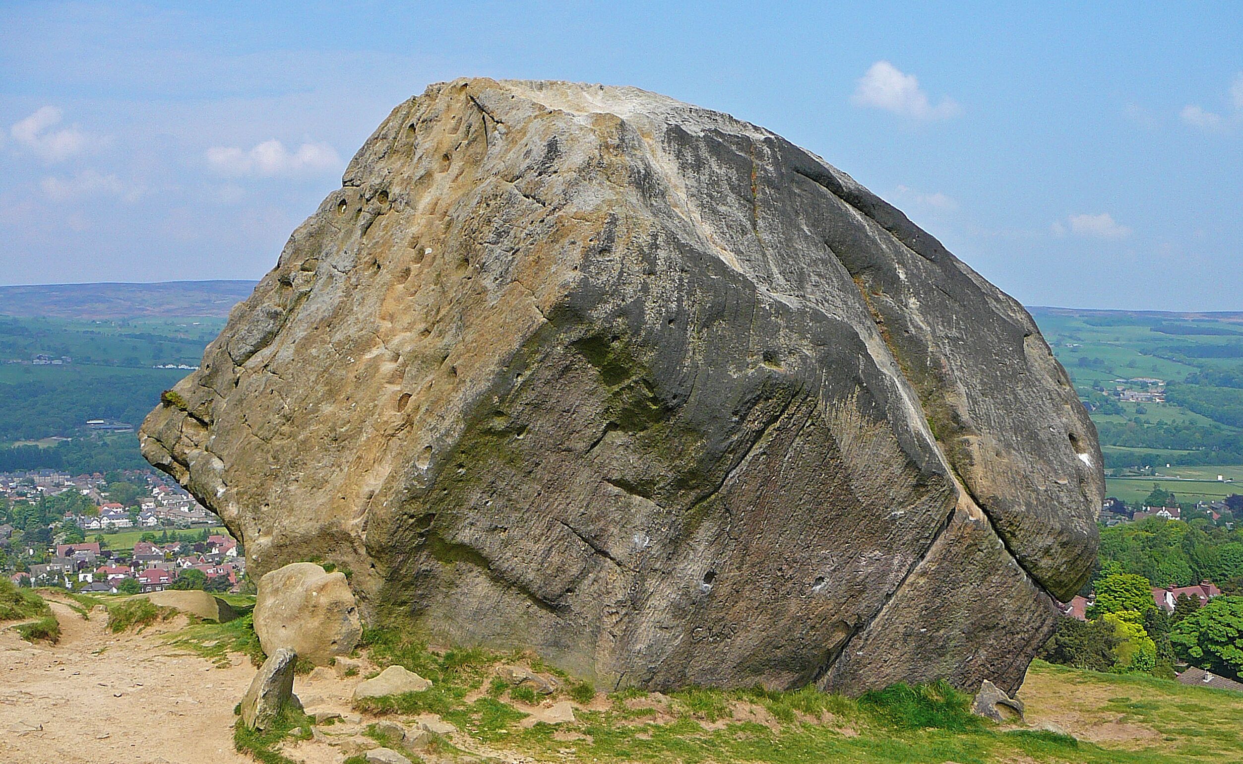 A large rock formation with a town in the background.