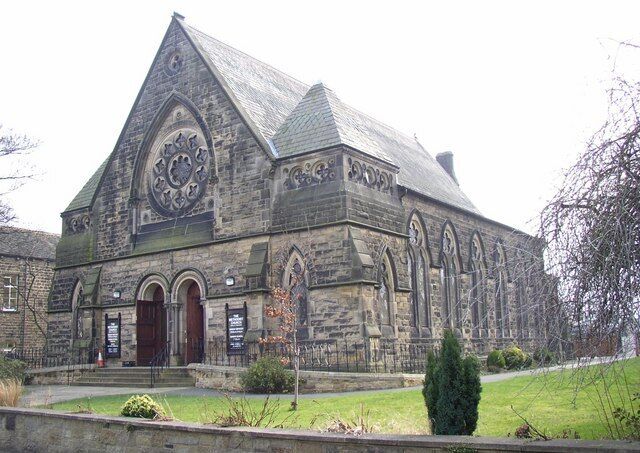 A large stone church with a pointed roof and a large circular window.