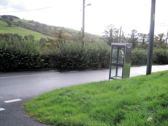 A rural road with a telephone booth on the side.