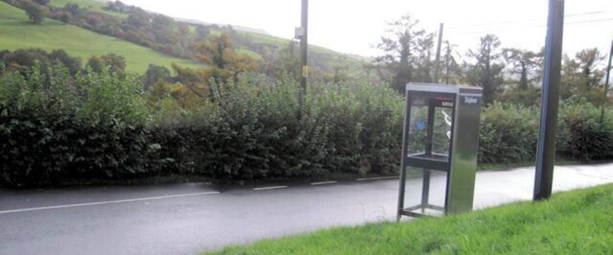 A rural road with a telephone booth on the side.